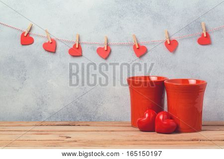 Valentines day concept with red coffee cups and heart shapes over rustic background