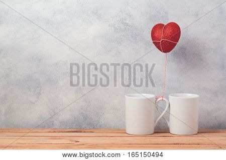 Valentines day concept with coffee cups and heart shape balloon over rustic background