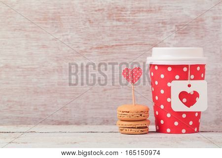Valentines day concept with paper coffee cup and macarons. Romantic coffee shop background