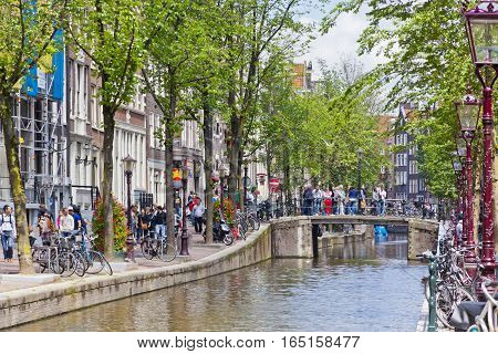AMSTERDAM NETHERLANDS - JUNE 23 2013: Lively street (Oudezijds Achterburgwal) in the heart of Red Light District in Amsterdam. View from Majoor Bosshardtbrug (bridge nr.211)