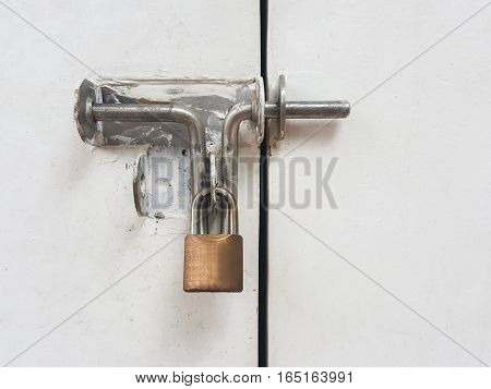 Rustic old padlock on white metal door