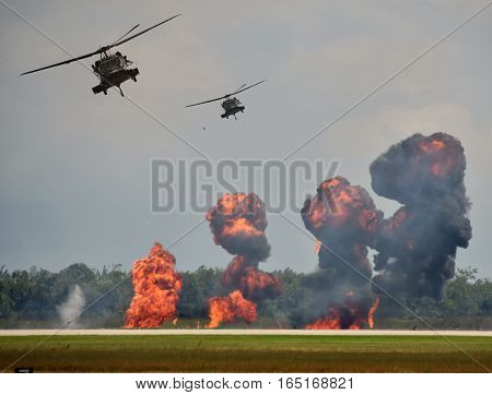 Military helicopters in ground attack with explosions