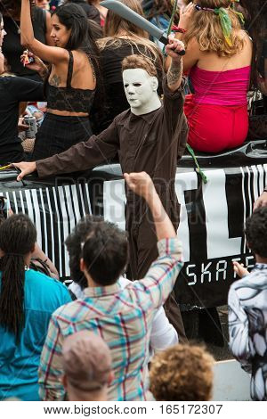 ATLANTA, GA - OCTOBER 2016:  A man wearing coveralls and a Michael Myers mask from the Halloween movie series wields a fake machete as he walks in the annual Little Five Points Halloween parade in Atlanta GA on October 15 2016.