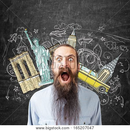 Portrait of a screaming young man with a long beard standing near a blackboard with New York sights drawn on it.