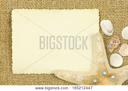 Reverse side of an old photo print with a decorative border sea star and sea sheels on sack cloth background