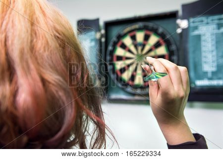 Closeup of young woman's head and hand throwing a dart
