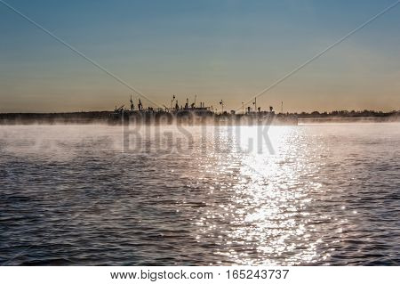 River landscape with fog during sunrise. Glittering water. Old barge background.