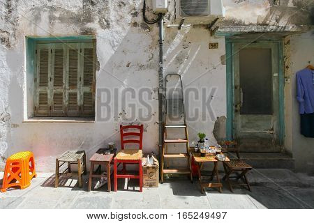 Rethymnon Island Crete Greece - June 23 2016: Wooden chairs ladder small tables with cups of frappe near the outside wall of old house located in Old Town of Rethymnon