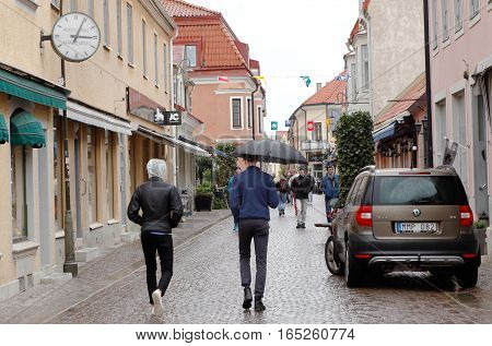 Visby Sweden - May 15 2016: People walking the street Adelsgatan in the Visby city center rainy day.