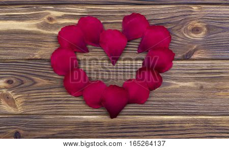 Flower Petals Forming A Heart Shape Ring Against Brown Wooden Background