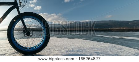 Fatbike also called fat bike or fat-tire bike - Cycling on large tire wheels. Cyclist goes to his bike on the frozen lake.