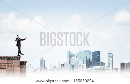 Businessman with blindfolder on eyes walking on building top