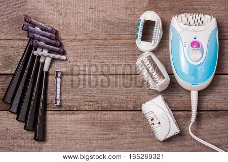 electric epilator with a razor on a light wooden background.