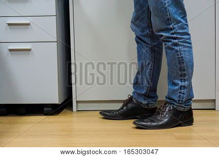 Close up men wear blue jean and brown leather shoes on floor.