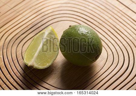 fresh green lemon on wooden background, closeup