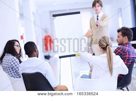Businessman giving a presentation to his colleagues at work standing in front of a flipchart with notes and diagrams