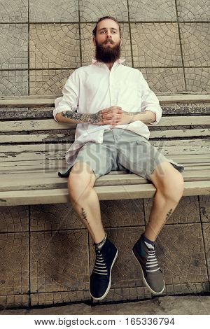 Cool Looking Guy With Tatoos And Long Beard Sitting On Chair