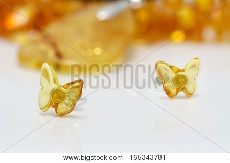 stud earrings from natural baltic amber on white acrilyc surface on background of amber beads