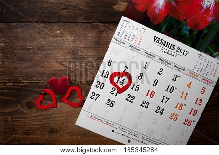 A calendar with hearts on the wooden table