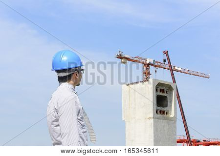 The construction engineer looking at the construction site and crain