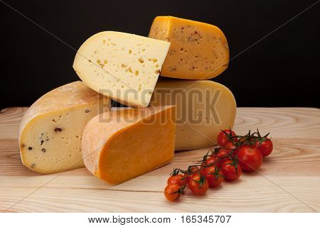 Different kinds of cheese and tomatoes on a wooden table