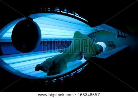 Beautiful slim blonde girl tans in the solarium