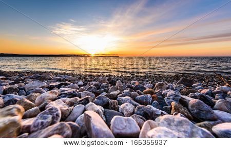 Stones On A Beach With Sunset On The Ocean Sea.
