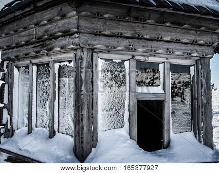Snow-covered windows a small wooden house facade made from wood carving