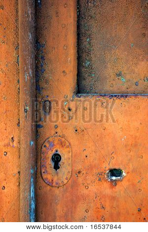 Arrugginito vecchia porta in legno dipinto in rosso, con keyhole metallico