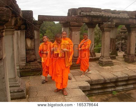 SIEM REAP, CAMBODIA - AUGUST 06, 2014 - Unidentified young buddhist monks walking inside the ruins of Baphuon temple
