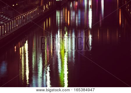 the reflection of light waves in the water Colored city lights reflected on water surface in night.
