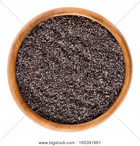 Ground gray poppy seeds in wooden bowl. Oilseed from opium poppy Paper somniferum, used as an ingredient in many foods or as oil. Isolated macro food photo close up on white background.