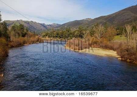 Curva blu dell'acqua del fiume coloma con colline verdi e lo sfondo blu cielo