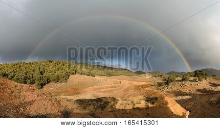 Panorama of a rainbow and dark clouds in the Ifrane National Park, Morocco.