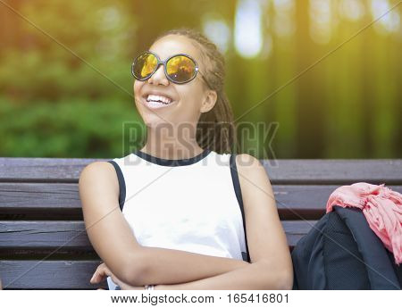 Happy and Smiling African American Teenage Girl With Long Dreadlocks Posing in Park Outdoors in Sunglasses. Horizontal Image Composition