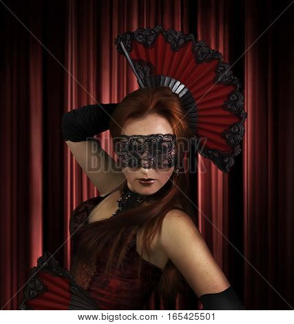Spanish dancer. A girl dancing spanish dance with folding fans on red curtain background photo.