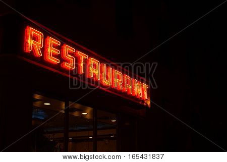 A neon sign displaying the word restaurant against a dark night background