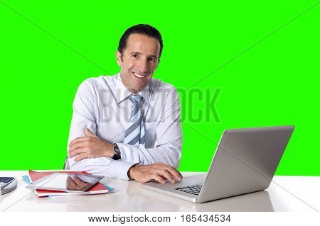 40 to 50 years old senior businessman working on computer laptop sitting at office desk looking confident relaxed and successful isolated on green chroma key screen background