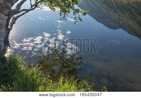 A still pond acts like a mirror and reflects a crystal clear view of an Alaskan hillside.