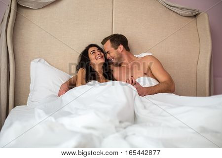Couple laughing in bed. Happy man and woman. Good morning, my love.