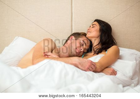 Lady with man in bed. Smiling people with closed eyes. Days spent together are priceless.