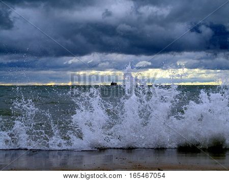 waves smashing against break wall with water intake crib on the horizon