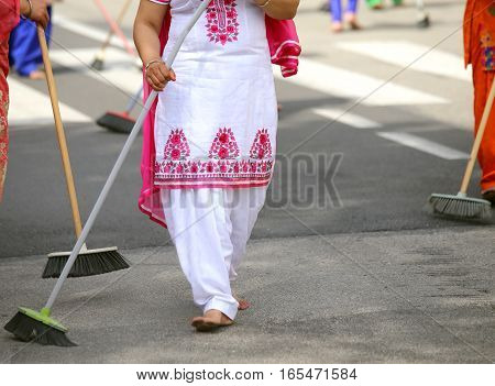 Barefoot Women With Colorful Clothes Sweep The Asphalt Road