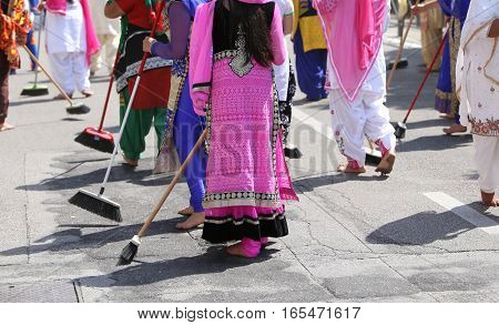 Women With Colorful Clothes Sweep The Asphalt Road During The Ce