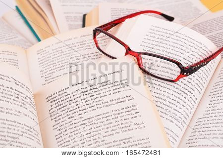 Opened books and eyeglasses close up picture.