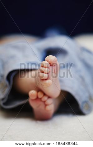 bare feet of newborn baby in jeans