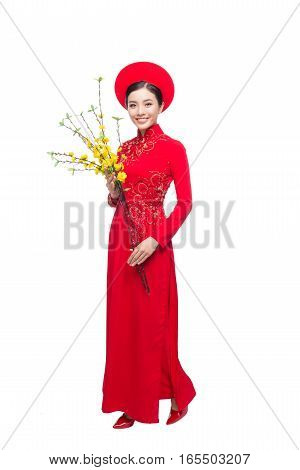 Portrait of a beautiful Asian woman on traditional festival costume Ao Dai holding Hoa Mai tree (Ochna Integerrima) flower. Tet holiday. Lunar New Year.