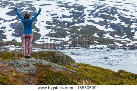 Travel freedom. Happy free tourist woman with arms raised outstretched up looking at landscape mountains covered with snow in Norway