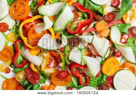 Mix of different red and yellow pepper and cucumber thin slices on white, pattern for textured background. Abstract art composition of fresh organic vegetables