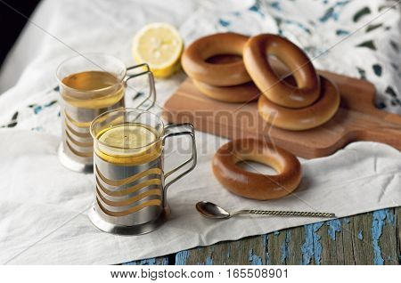 Mug of tea with lemon and bagels on a wooden background. Tea with lemon Baking bagels white tablecloth.